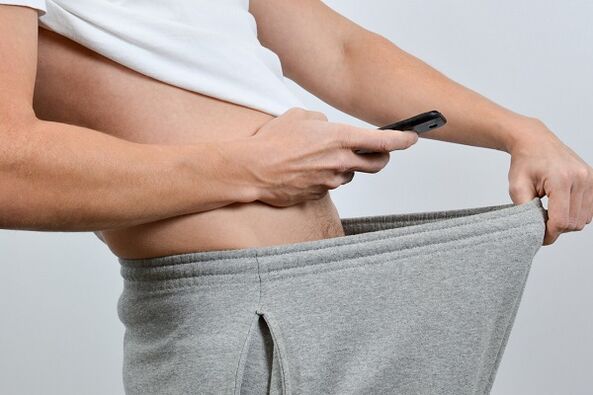 a man looks in his pants at an enlarged penis